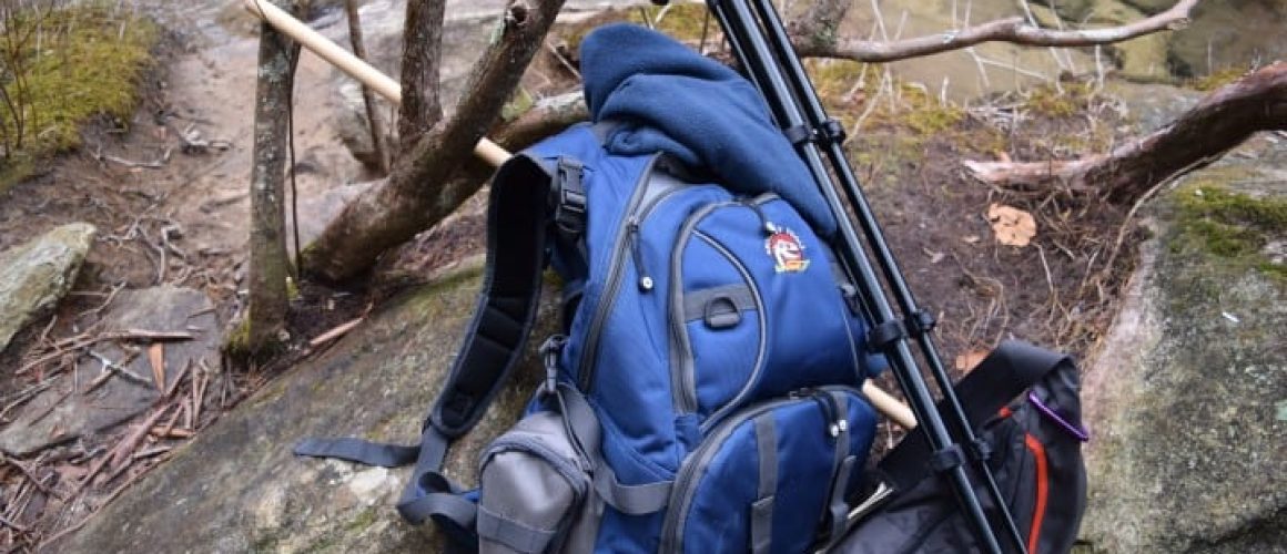 backpack and gear down by water on kayak trip