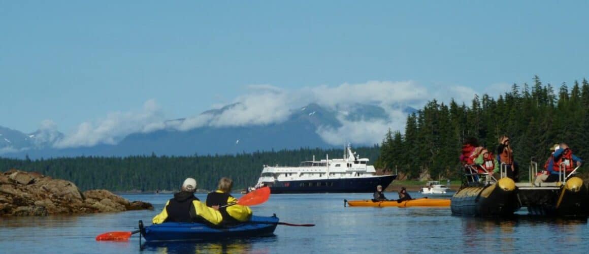 Kayakers paddling near boat in Alaska waters