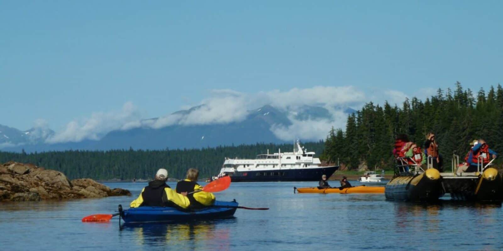 Kayakers paddling near boat in Alaska waters